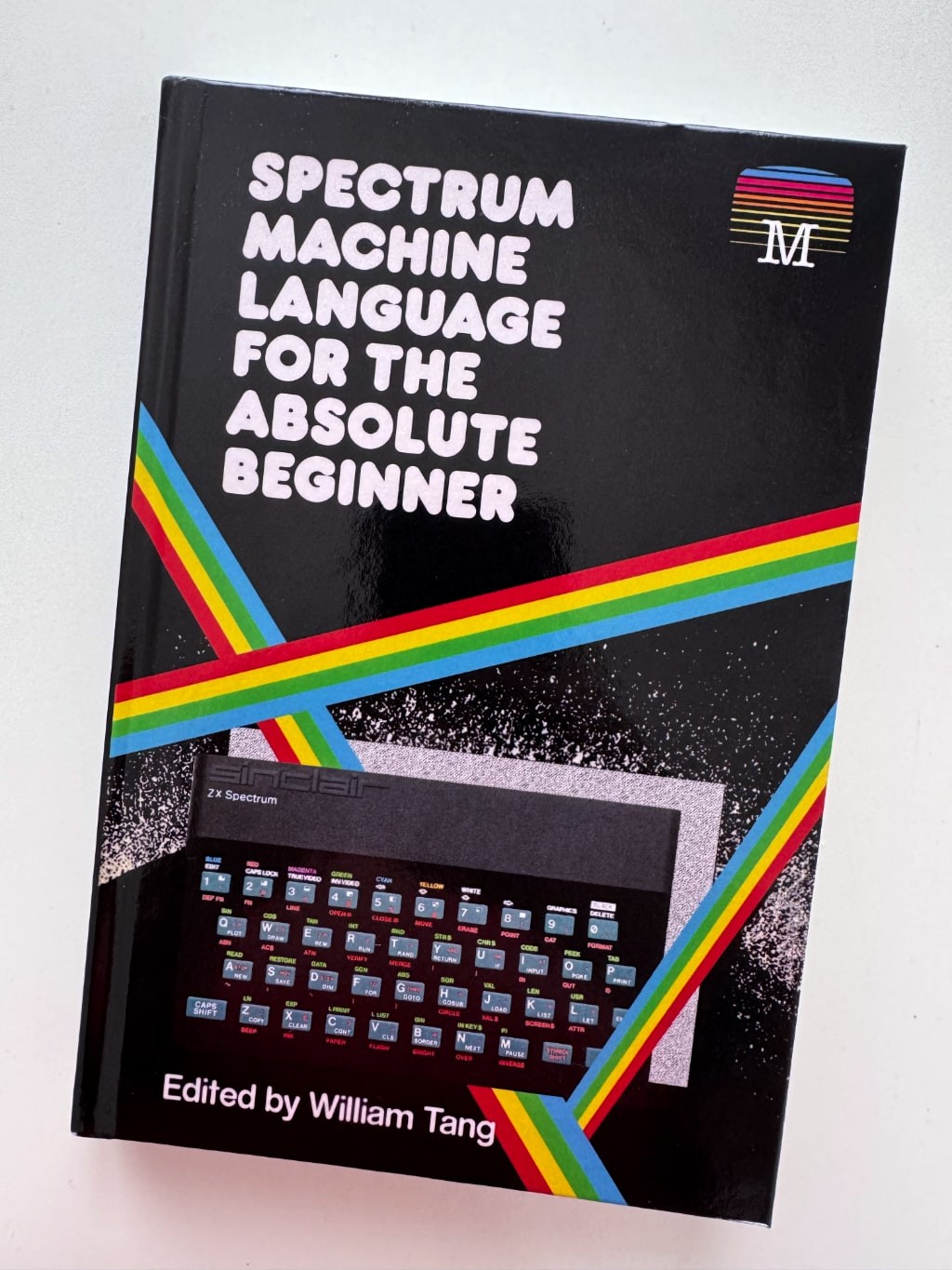 A photo of the cover of "SPECTRUM MACHINE LANGUAGE FOR THE ABSOLUTE BEGINNER" with author info "Edited by William Tang". 
The original Sinclair ZX Spectrum is shown on the cover with its (in?)famous rubber keyboard.